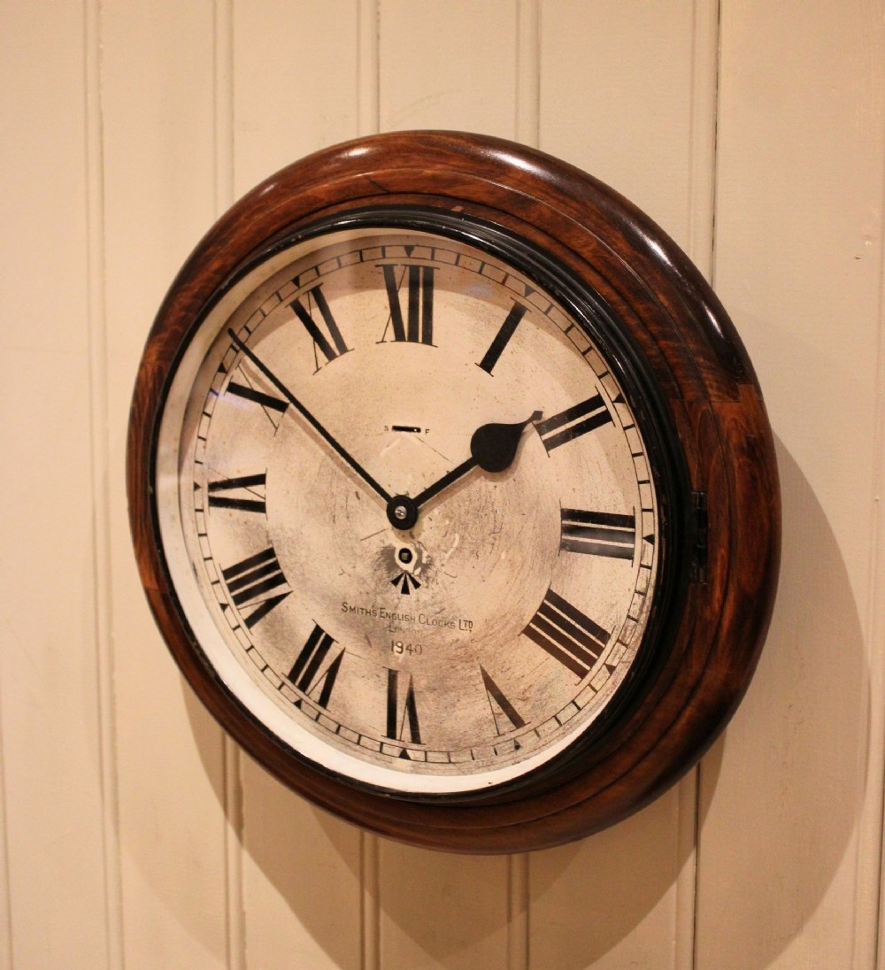 A circular 1940s wall clock featuring a turned beech wood bezel surround and an aged dial with black Roman numerals. View V