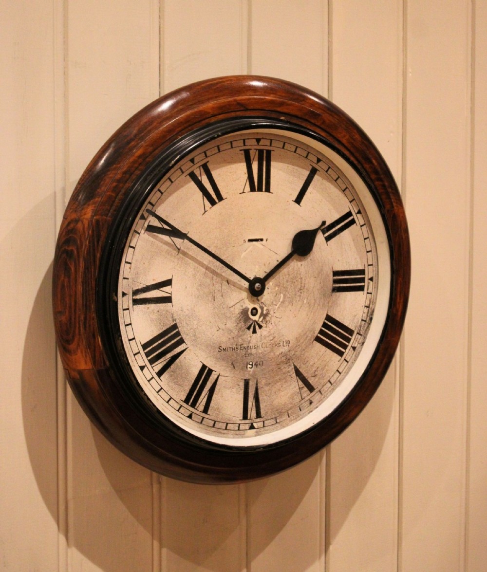 A circular 1940s wall clock featuring a turned beech wood bezel surround and an aged dial with black Roman numerals. View VIII