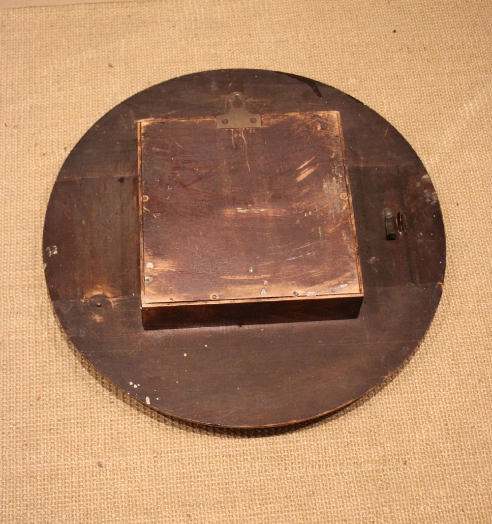 A circular 1940s wall clock featuring a turned beech wood bezel surround and an aged dial with black Roman numerals. View XII