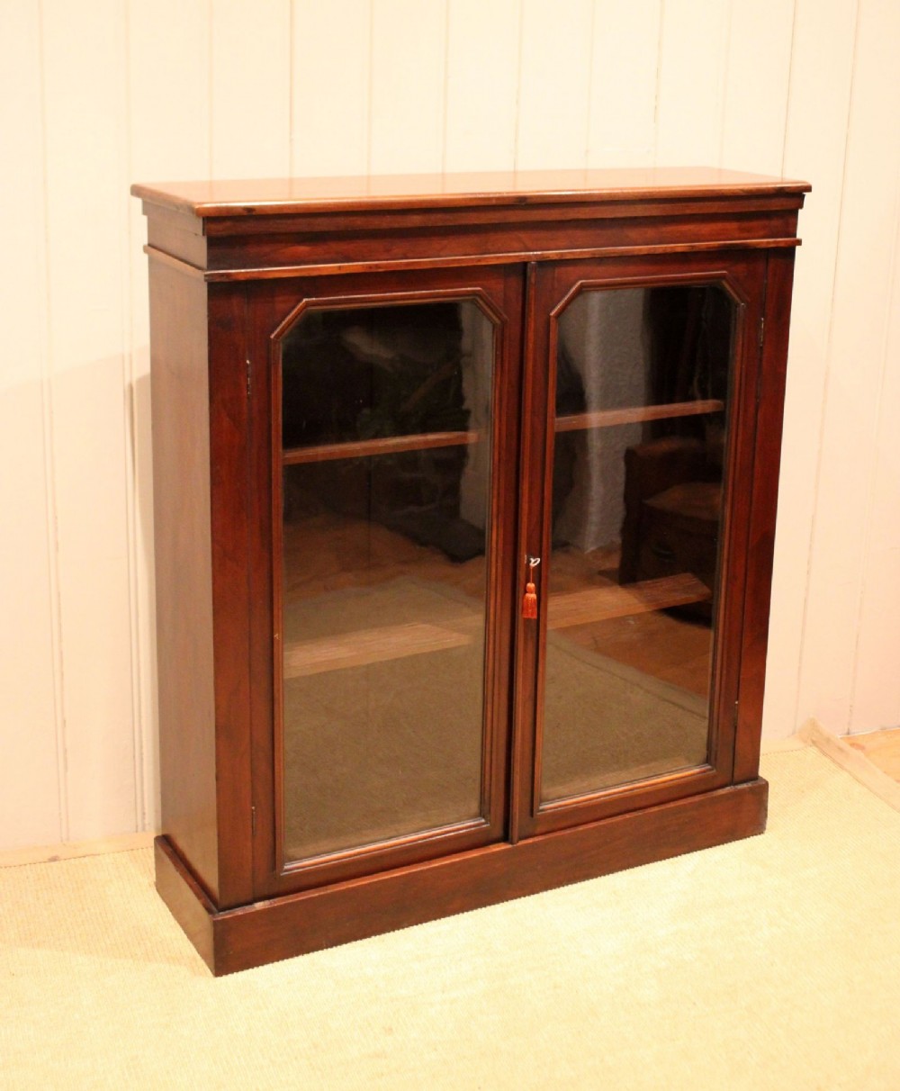 A late nineteenth-century dark mahogany bookcase with two glazed doors and interior shelves containing rows of books. View XII