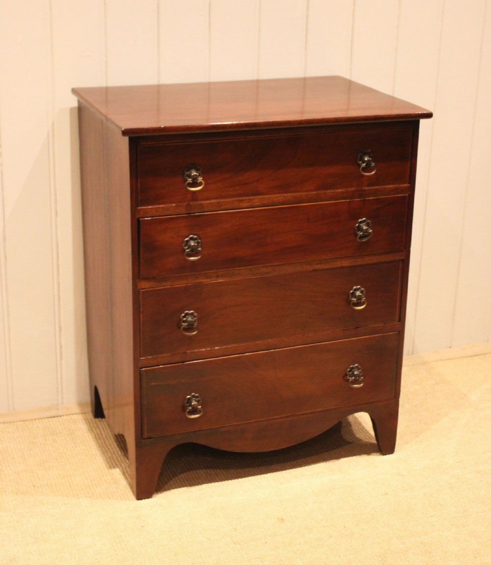 An Edwardian mahogany chest of drawers with four graduated drawers, circular brass handles, and a shaped apron base. View III