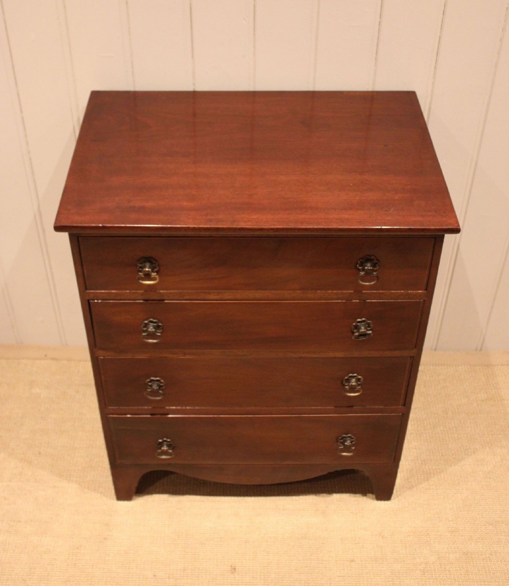 An Edwardian mahogany chest of drawers with four graduated drawers, circular brass handles, and a shaped apron base. View VI