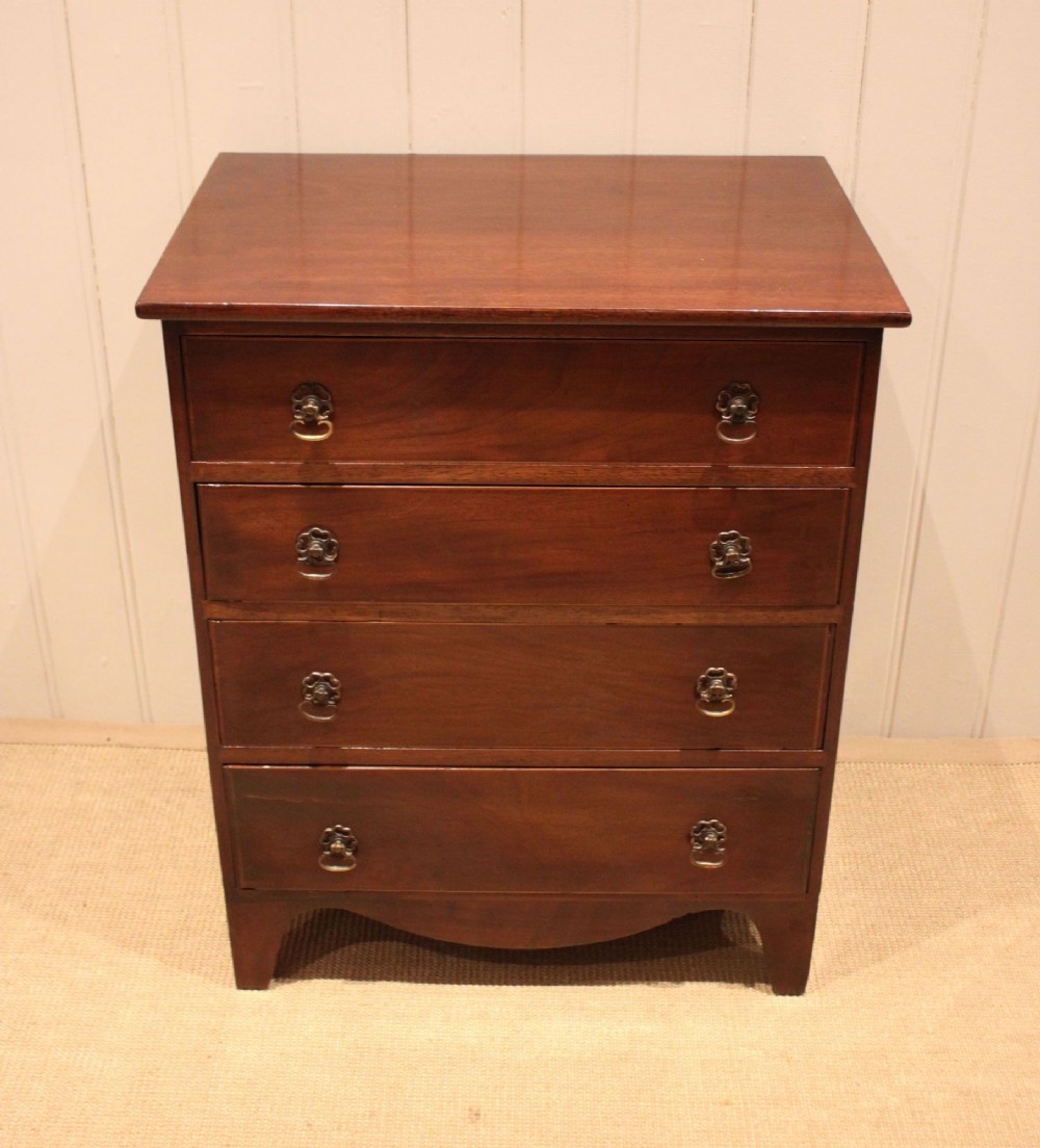 An Edwardian mahogany chest of drawers with four graduated drawers, circular brass handles, and a shaped apron base. View XI