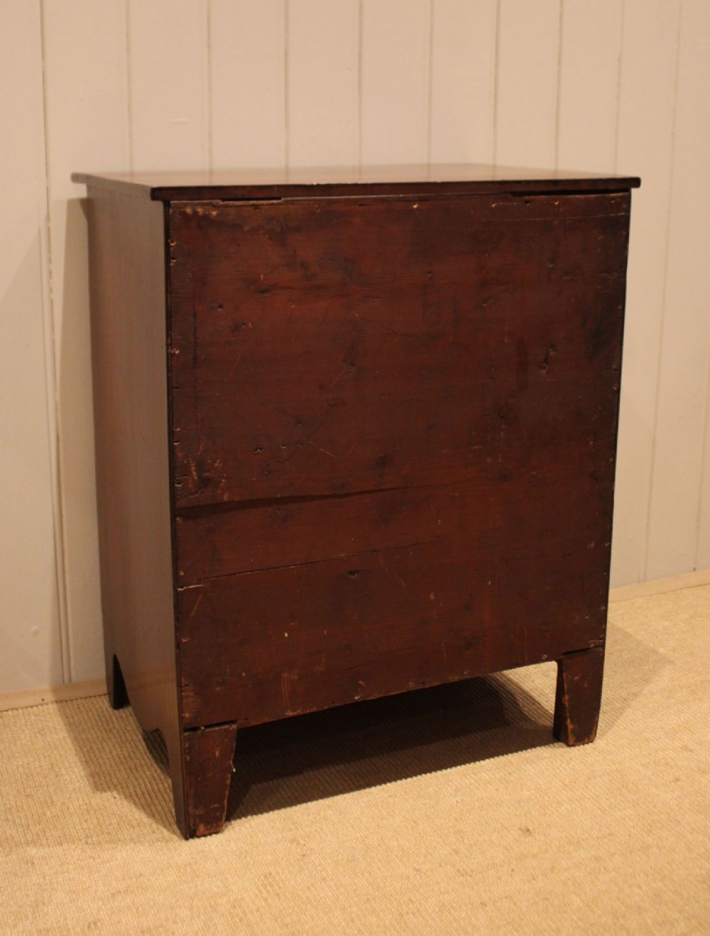 An Edwardian mahogany chest of drawers with four graduated drawers, circular brass handles, and a shaped apron base. View XII