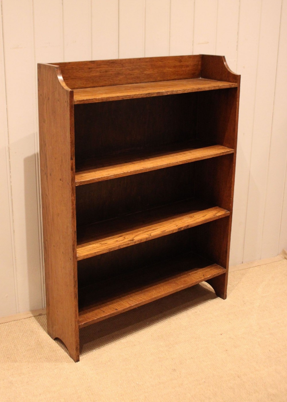 A golden oak open bookcase featuring four tiered shelves filled with antique books and a shaped top upstand gallery. View II
