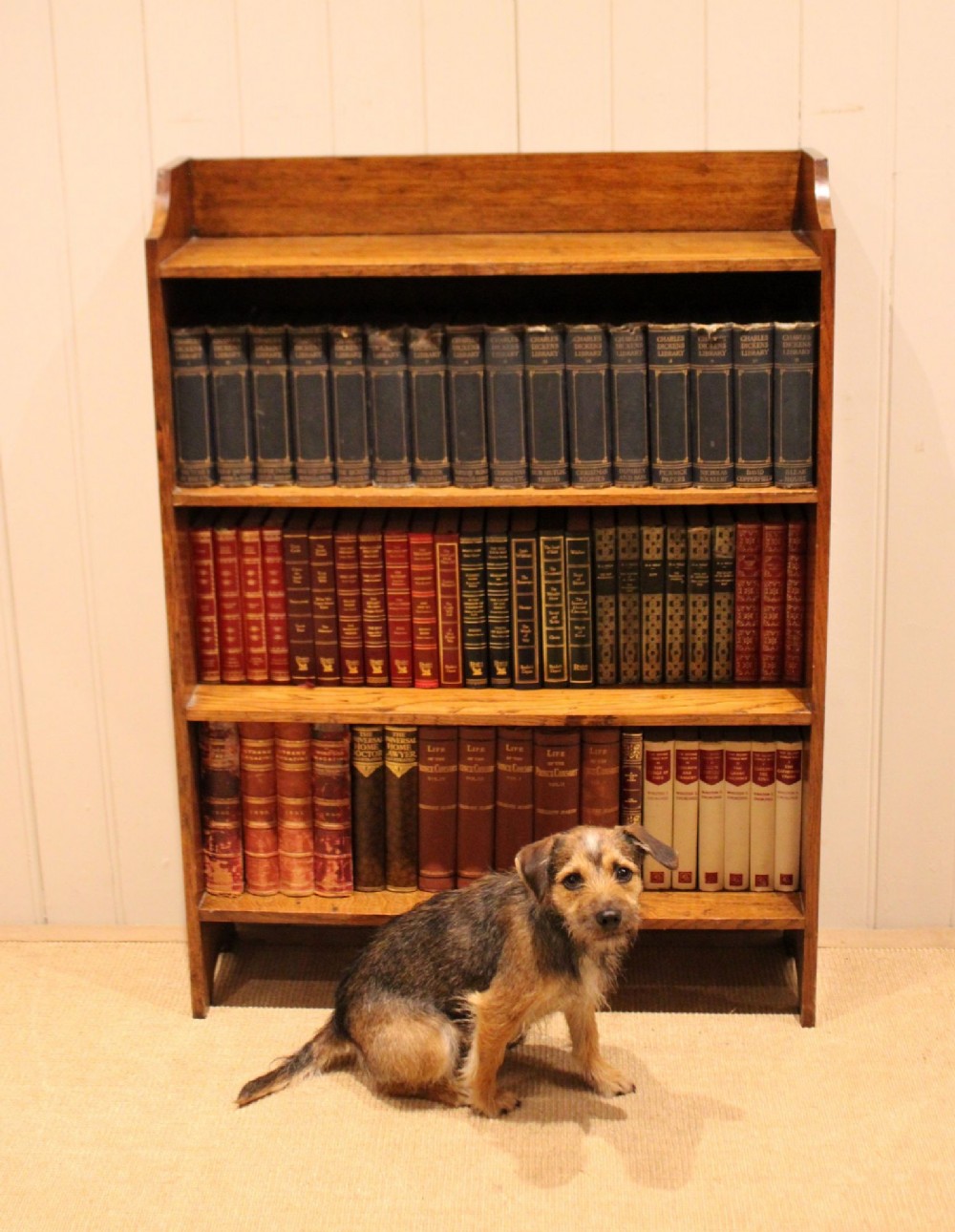 A golden oak open bookcase featuring four tiered shelves filled with antique books and a shaped top upstand gallery. View VII