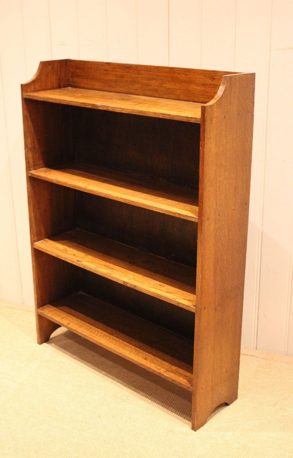 A golden oak open bookcase featuring four tiered shelves filled with antique books and a shaped top upstand gallery. View VIII