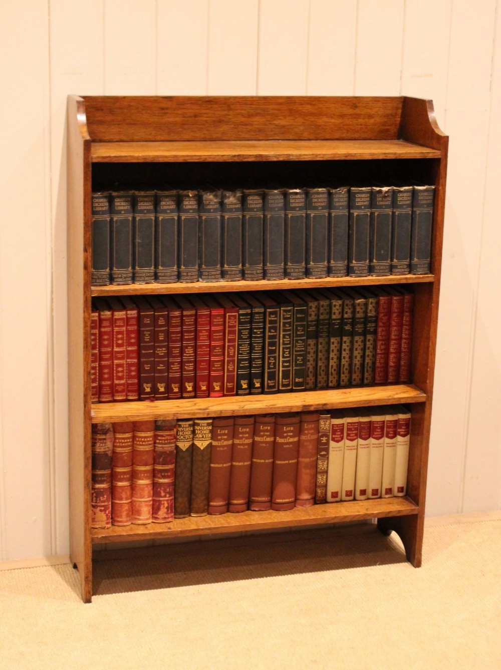 A golden oak open bookcase featuring four tiered shelves filled with antique books and a shaped top upstand gallery. View IX