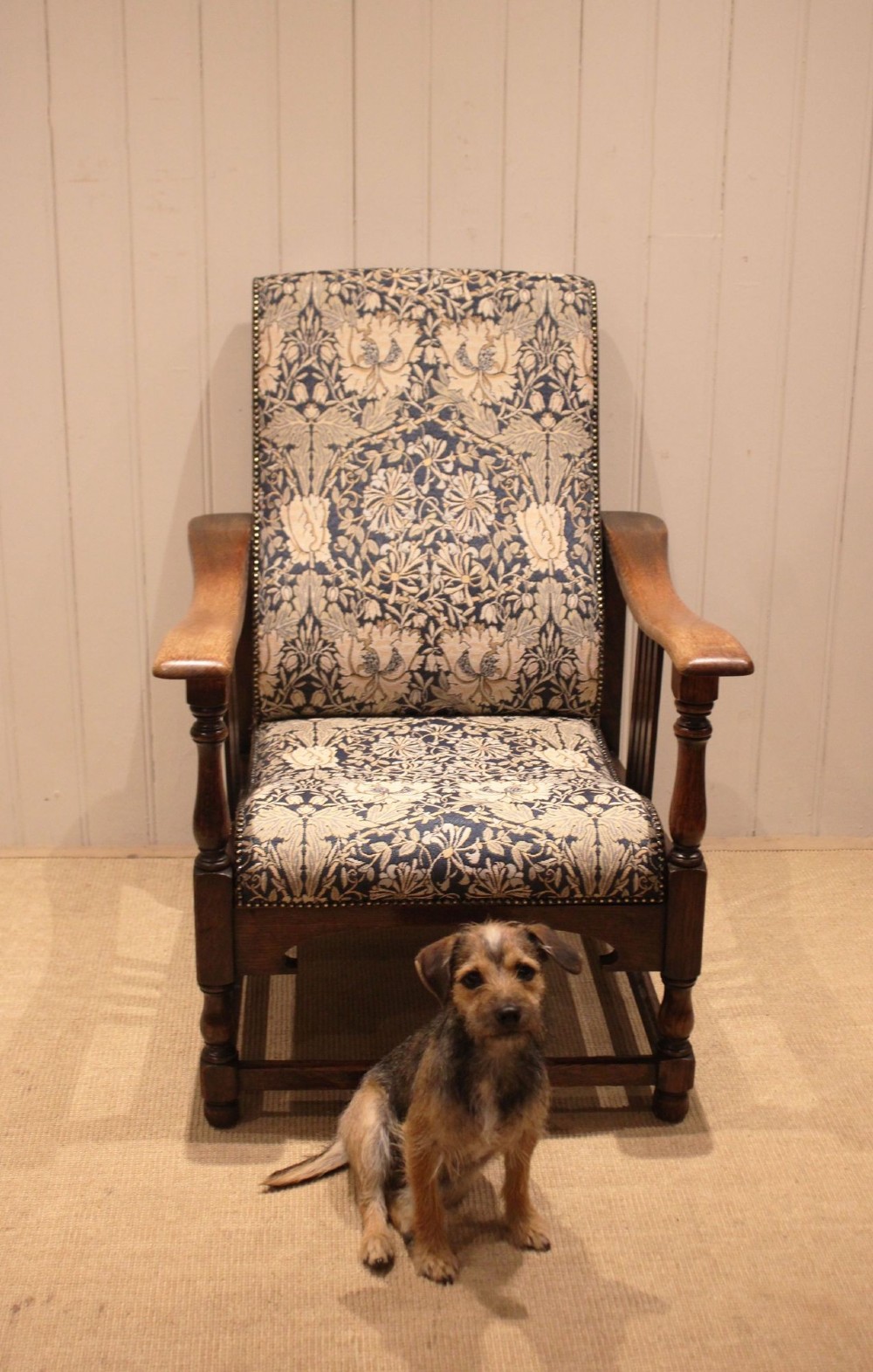 An Arts and Crafts oak reclining armchair featuring slatted sides, turned front legs, wide armrests, and floral pattern upholstery in blue and cream tones. View III