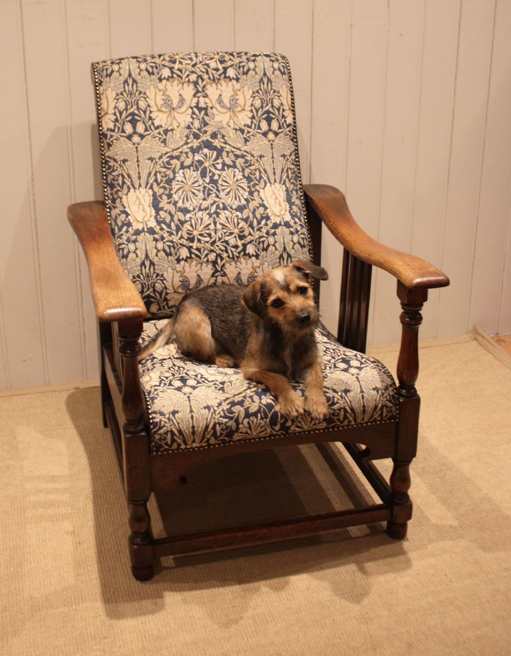 An Arts and Crafts oak reclining armchair featuring slatted sides, turned front legs, wide armrests, and floral pattern upholstery in blue and cream tones. View VIII