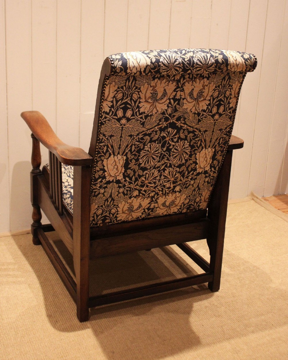An Arts and Crafts oak reclining armchair featuring slatted sides, turned front legs, wide armrests, and floral pattern upholstery in blue and cream tones. View XIV