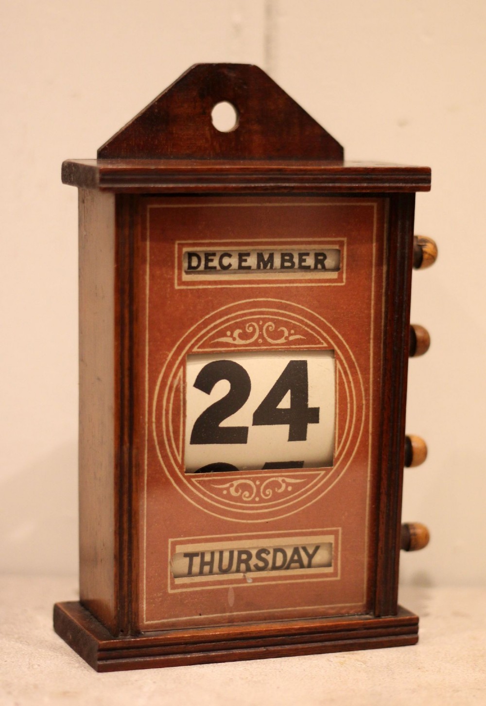 A late nineteenth-century mahogany perpetual desk calendar with turned wooden side knobs, displaying the date Saturday March 10. View II