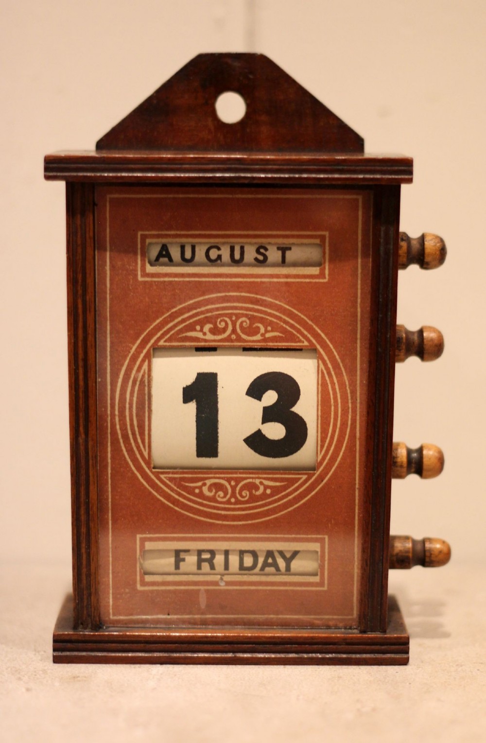 A late nineteenth-century mahogany perpetual desk calendar with turned wooden side knobs, displaying the date Saturday March 10. View III