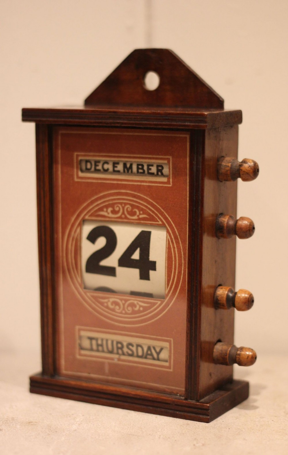 A late nineteenth-century mahogany perpetual desk calendar with turned wooden side knobs, displaying the date Saturday March 10. View V