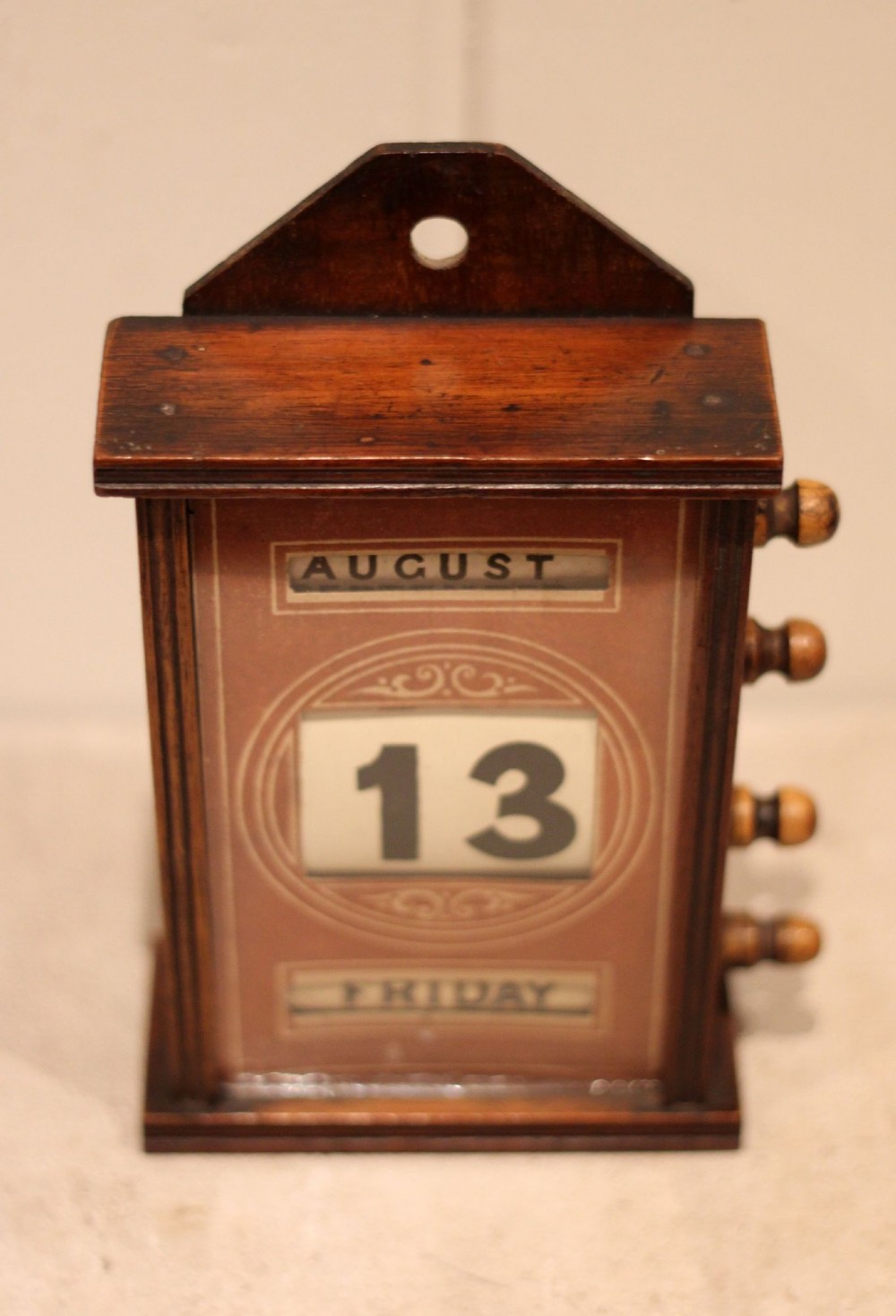 A late nineteenth-century mahogany perpetual desk calendar with turned wooden side knobs, displaying the date Saturday March 10. View VI