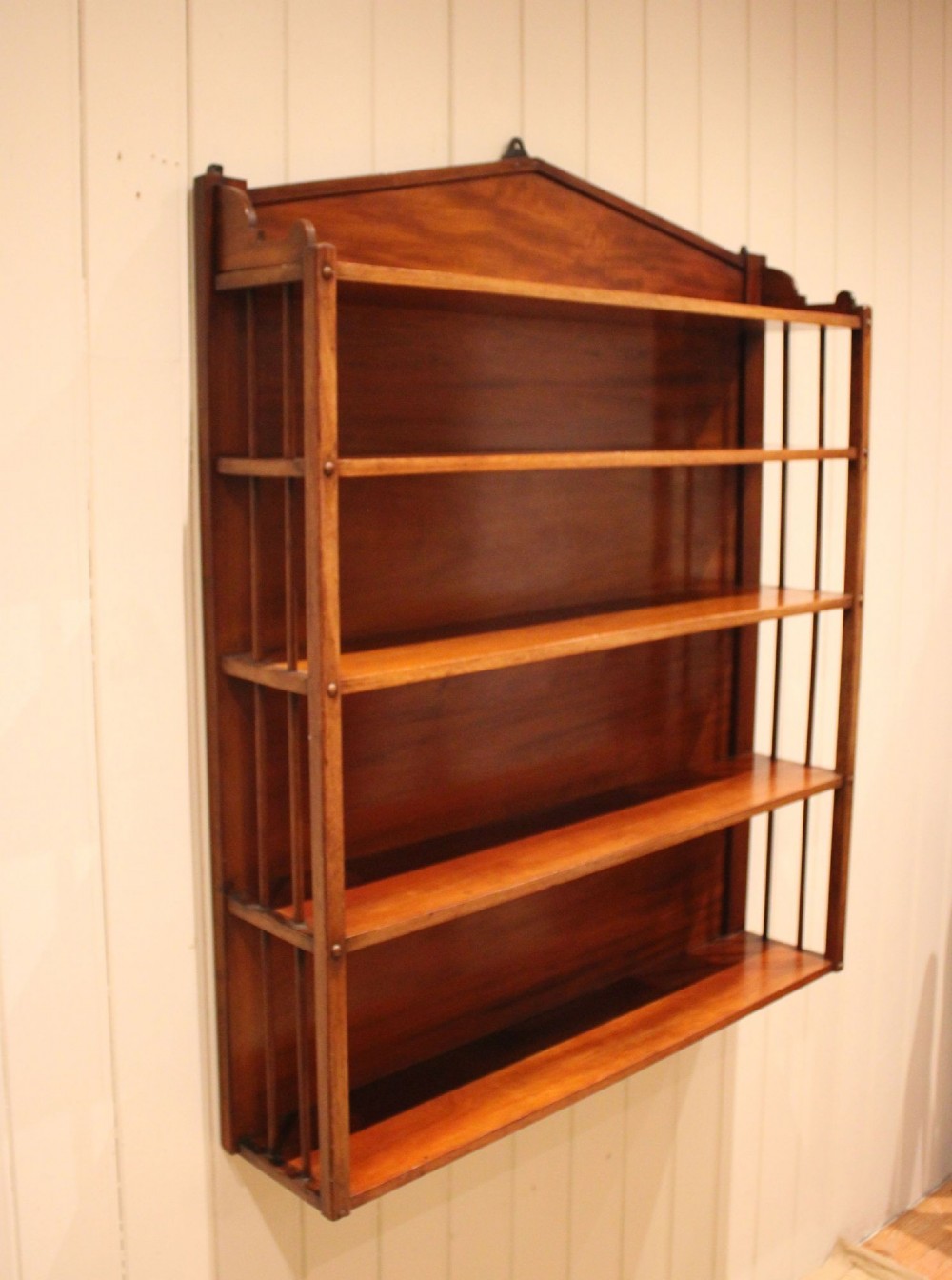 A four-tier mahogany wall-mounted shelving unit featuring open spindled sides and a peaked pediment top. View VI