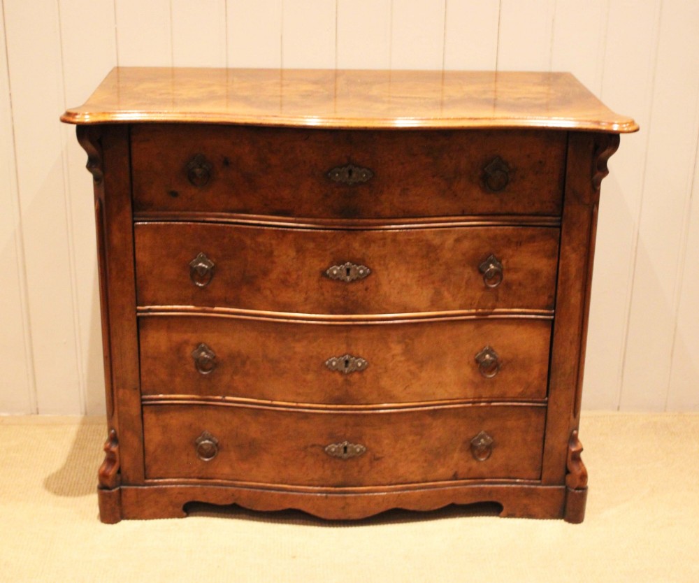 A mid-19th century burr walnut chest of four graduated drawers with a serpentine contoured front and brass drop handles.