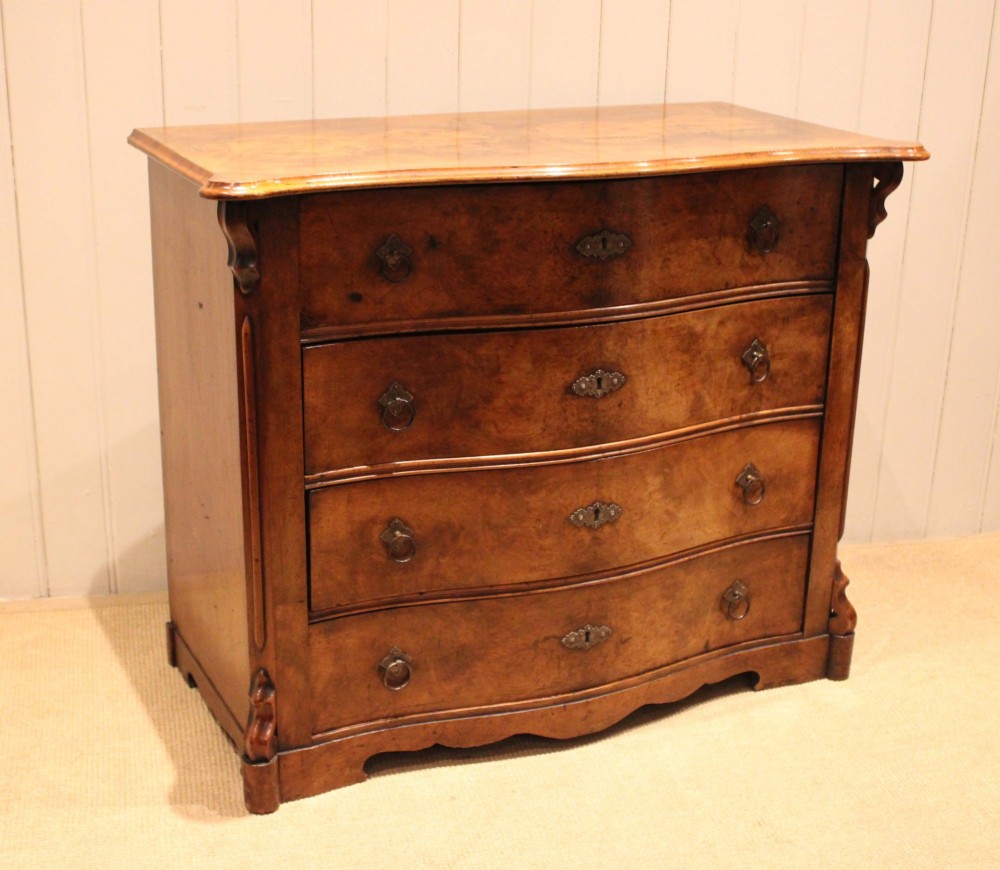 A mid-19th century burr walnut chest of four graduated drawers with a serpentine contoured front and brass drop handles. View II