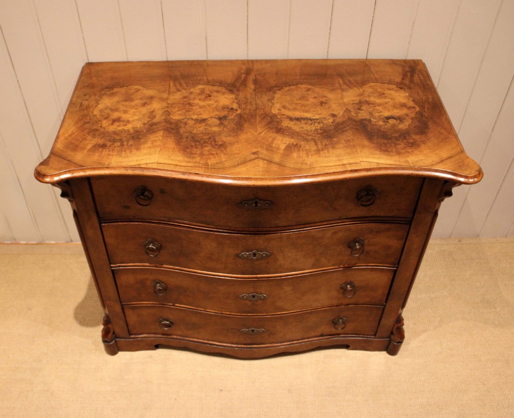 A mid-19th century burr walnut chest of four graduated drawers with a serpentine contoured front and brass drop handles. View III