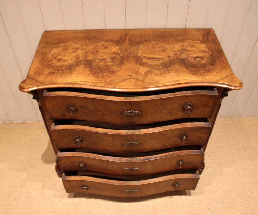 A mid-19th century burr walnut chest of four graduated drawers with a serpentine contoured front and brass drop handles. View V