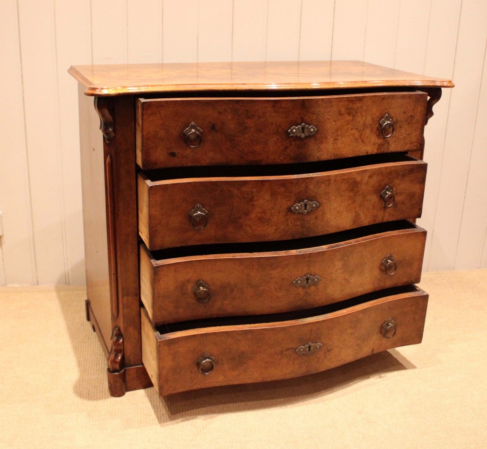A mid-19th century burr walnut chest of four graduated drawers with a serpentine contoured front and brass drop handles. View VI
