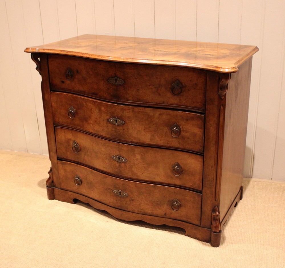 A mid-19th century burr walnut chest of four graduated drawers with a serpentine contoured front and brass drop handles. View VII