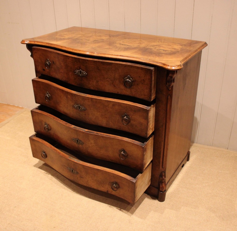 A mid-19th century burr walnut chest of four graduated drawers with a serpentine contoured front and brass drop handles. View VIII