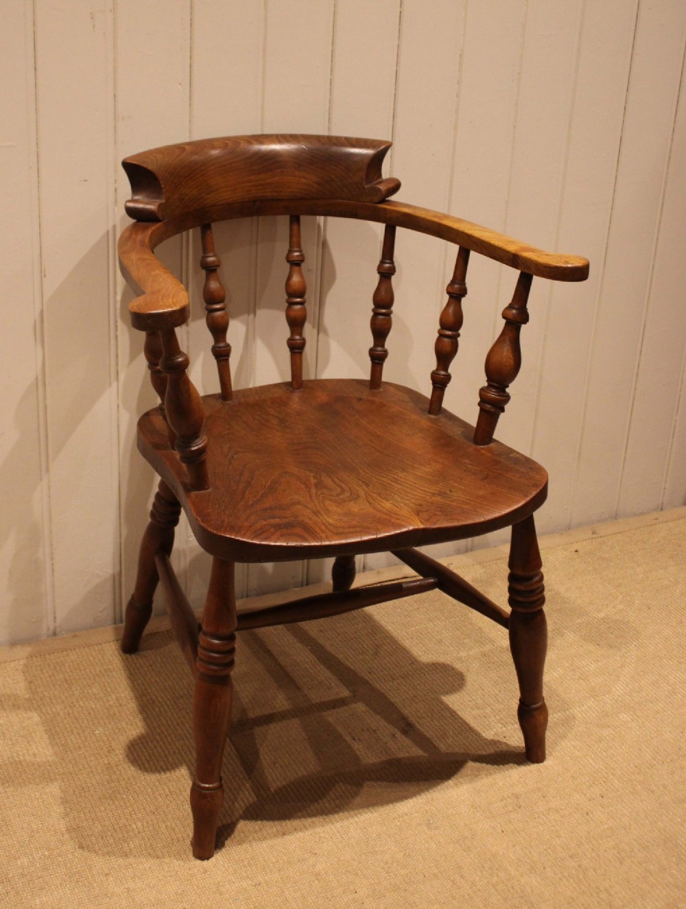 A late 19th-century wooden smokers bow armchair featuring a curved top rail, turned spindles, contoured saddle seat, and turned legs. View IV