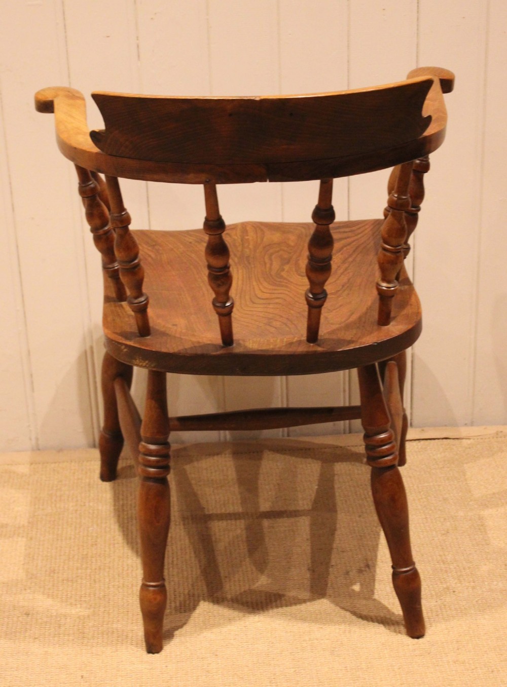 A late 19th-century wooden smokers bow armchair featuring a curved top rail, turned spindles, contoured saddle seat, and turned legs. View VI