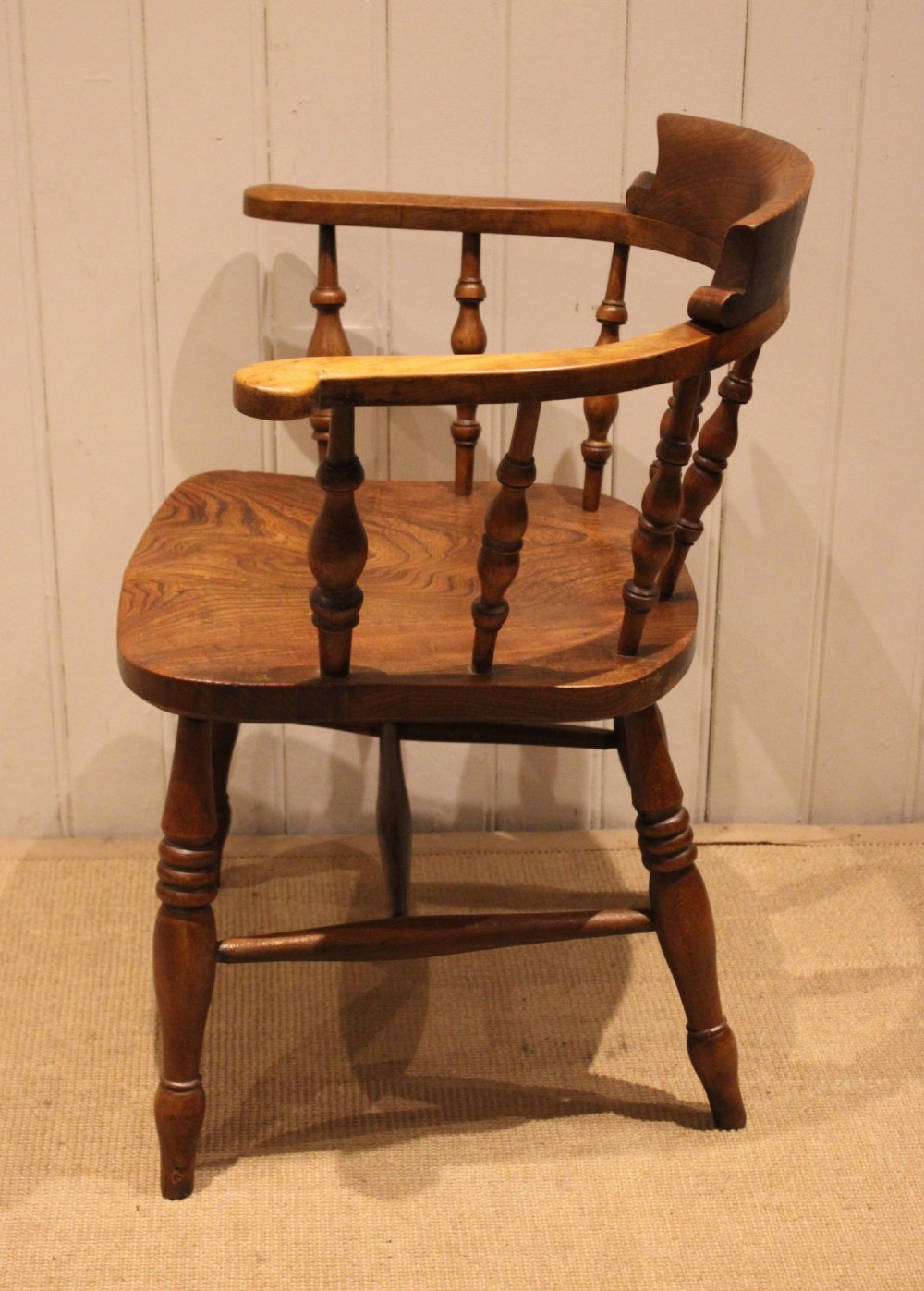 A late 19th-century wooden smokers bow armchair featuring a curved top rail, turned spindles, contoured saddle seat, and turned legs. View VII