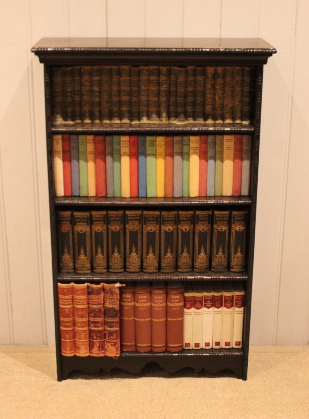 An antique dark oak open bookcase featuring four fixed shelves decorated with beaded edge mouldings and a shaped base plinth. View III