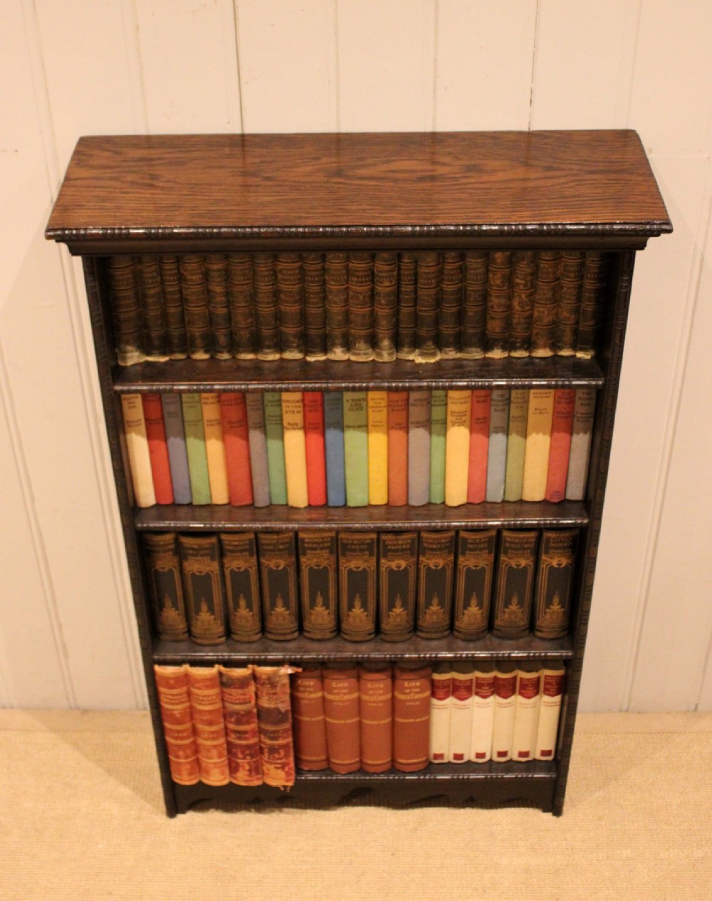 An antique dark oak open bookcase featuring four fixed shelves decorated with beaded edge mouldings and a shaped base plinth. View VII
