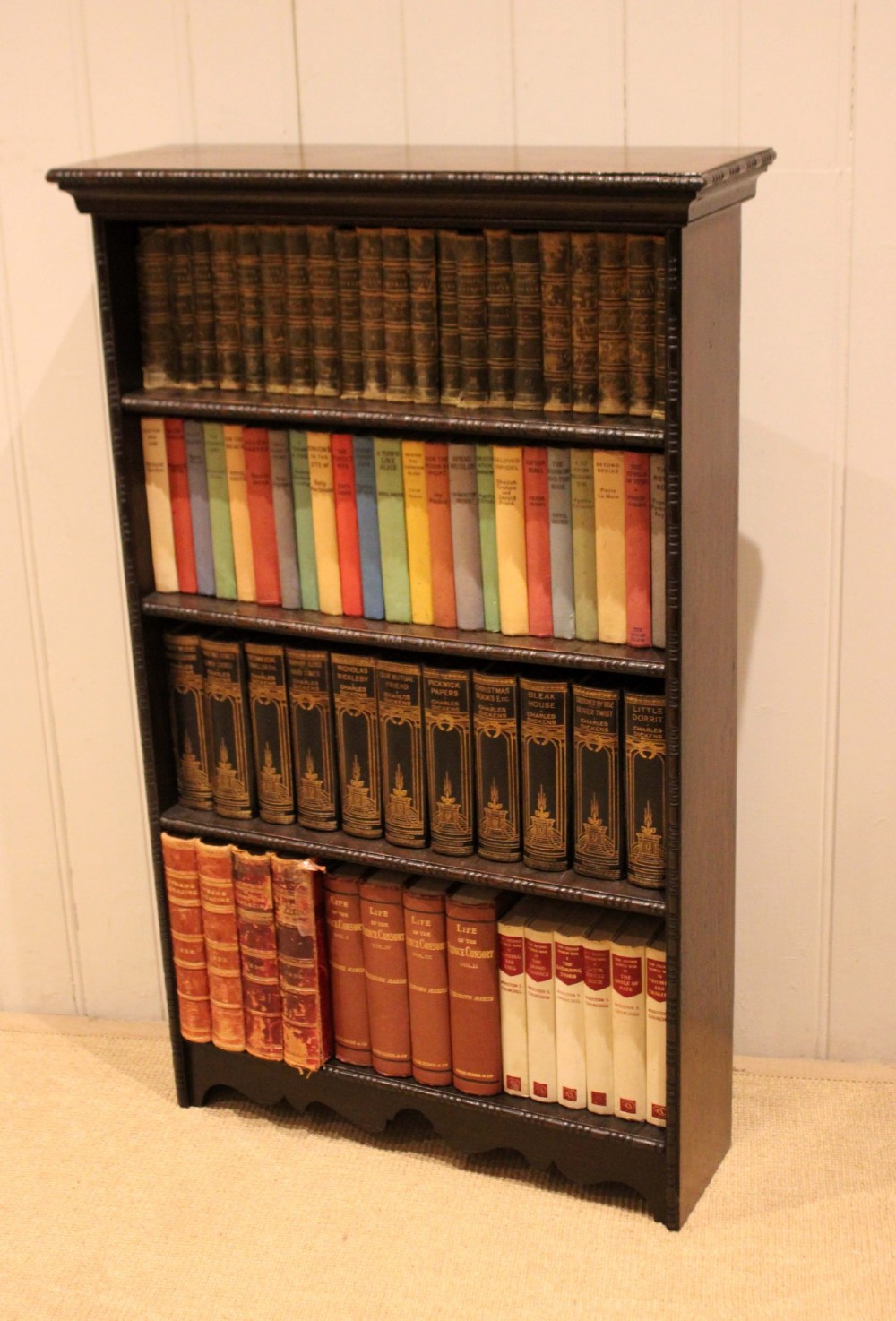 An antique dark oak open bookcase featuring four fixed shelves decorated with beaded edge mouldings and a shaped base plinth. View XI