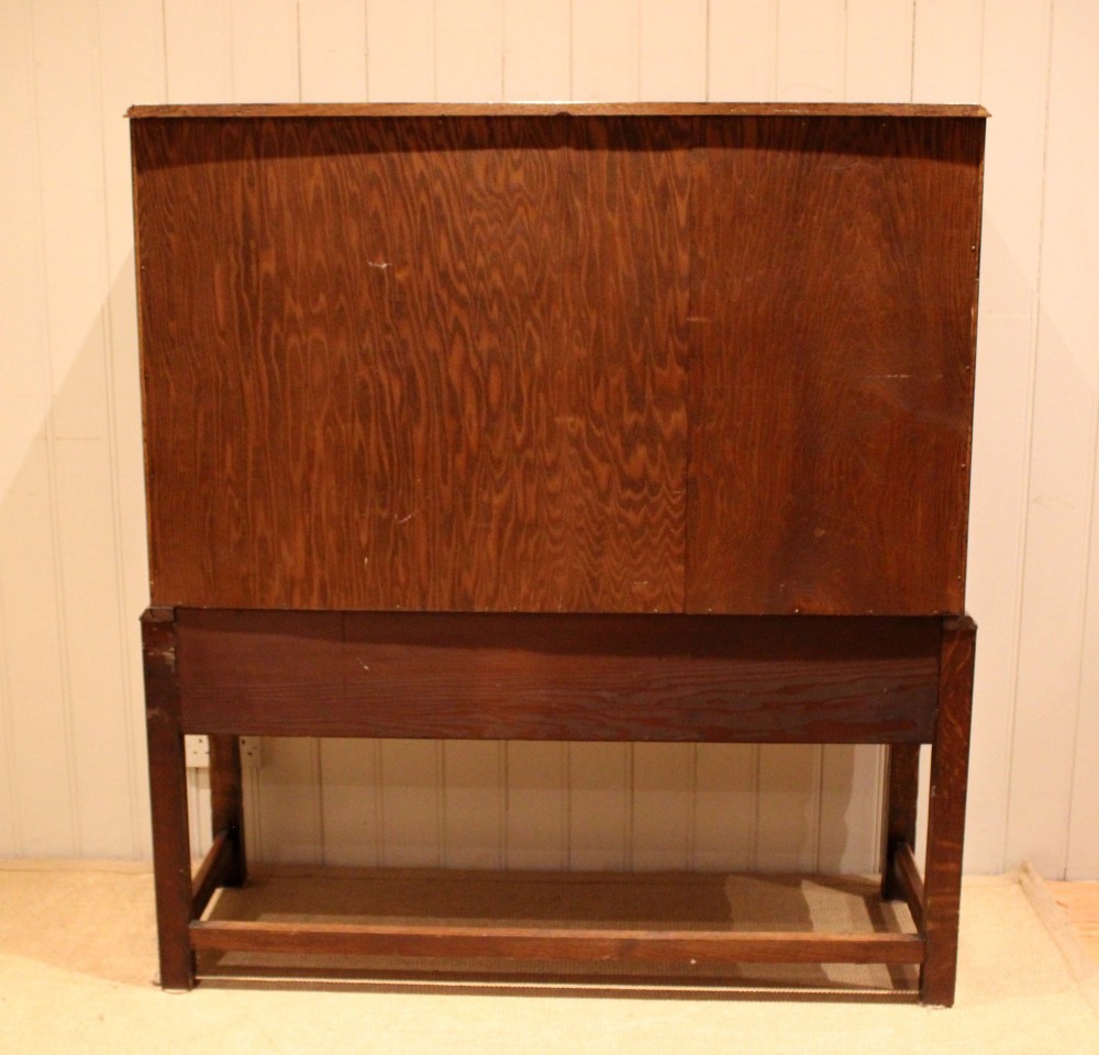 A solid oak side cabinet featuring three carved panel doors above three short drawers on square legs. View XII