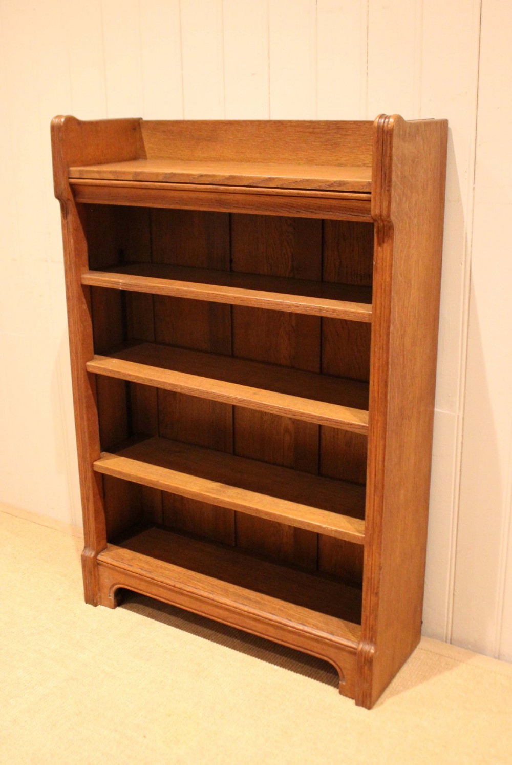 A freestanding light oak open bookcase featuring four horizontal shelves, a raised gallery rail, and curved side brackets. View II