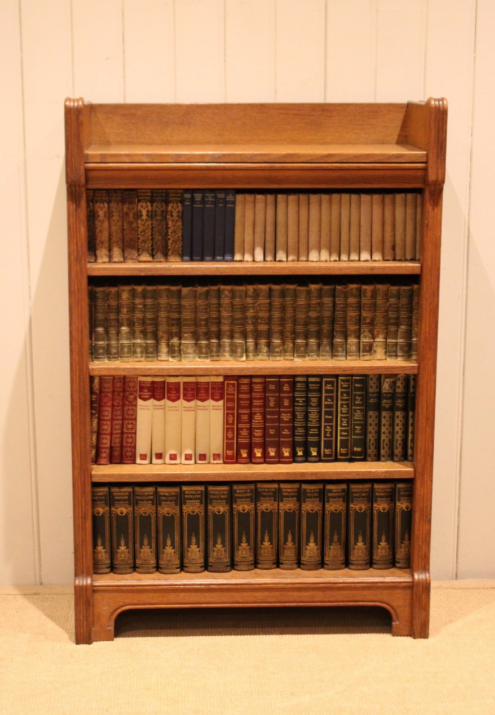 A freestanding light oak open bookcase featuring four horizontal shelves, a raised gallery rail, and curved side brackets. View III