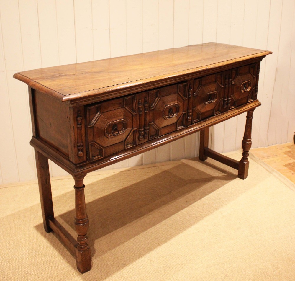 A Jacobean style carved oak dresser base with two geometric moulded drawers, split spindle mouldings, and turned front legs. View VIII