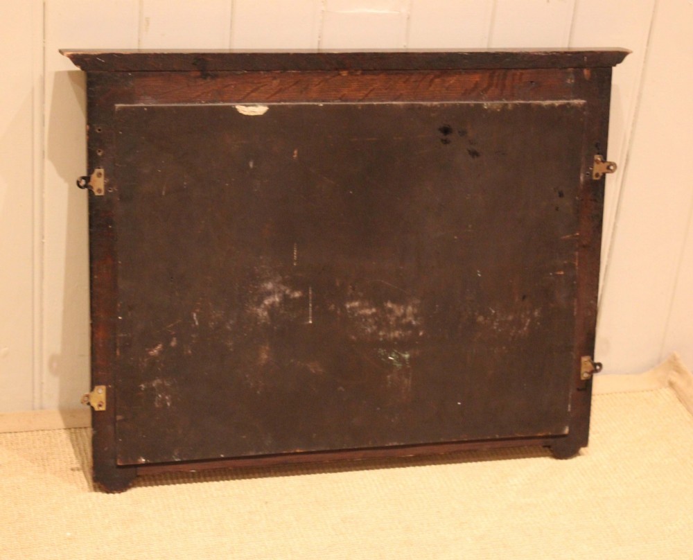 A dark oak rectangular wall mirror featuring six turned wooden coat pegs framing the glass plate, decorated with beaded trim and a carved central boss on the top rail. View XII