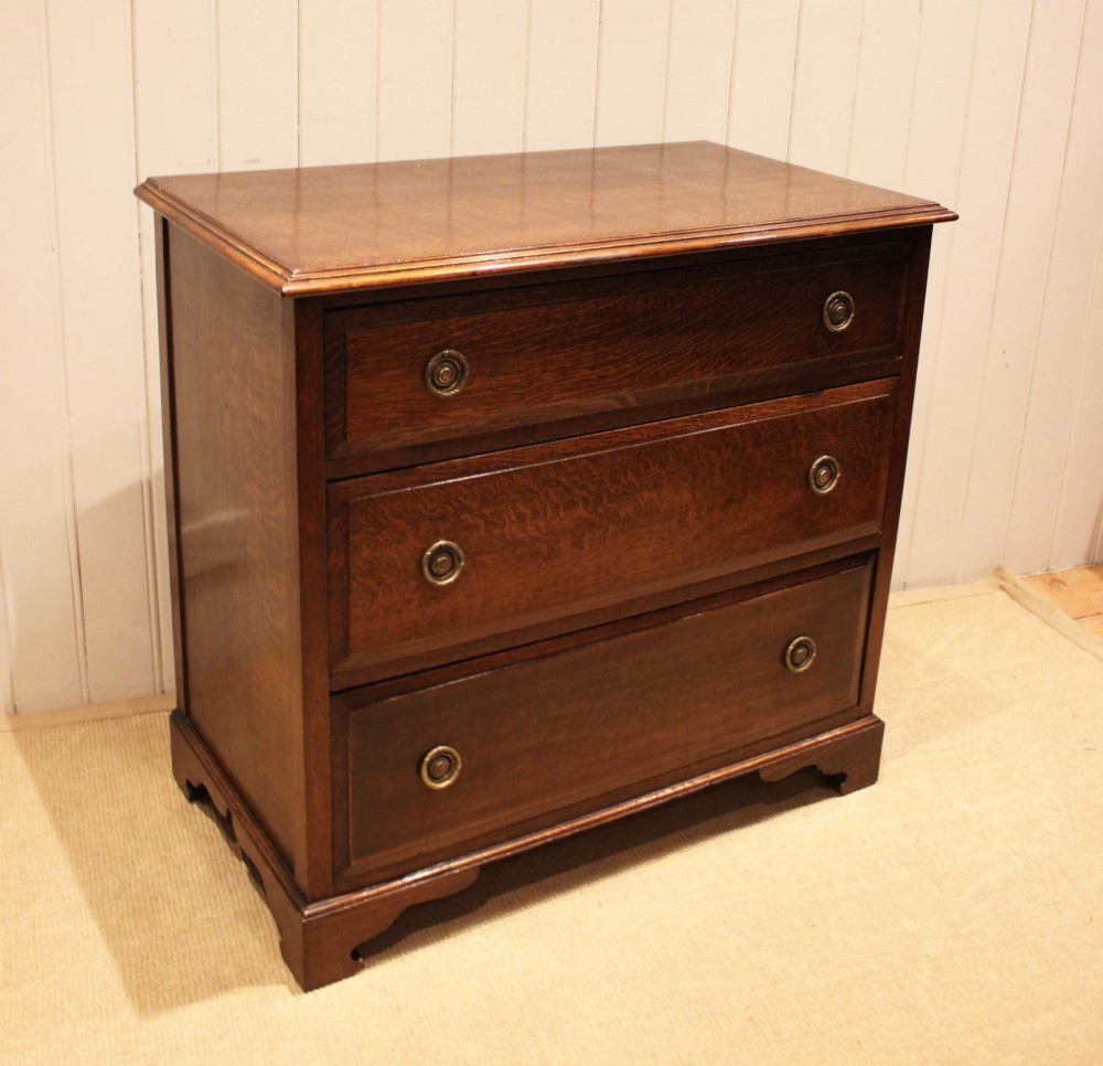 A solid oak chest of drawers featuring three full-width drawers with circular brass drop ring handles and bracket feet. View VIII