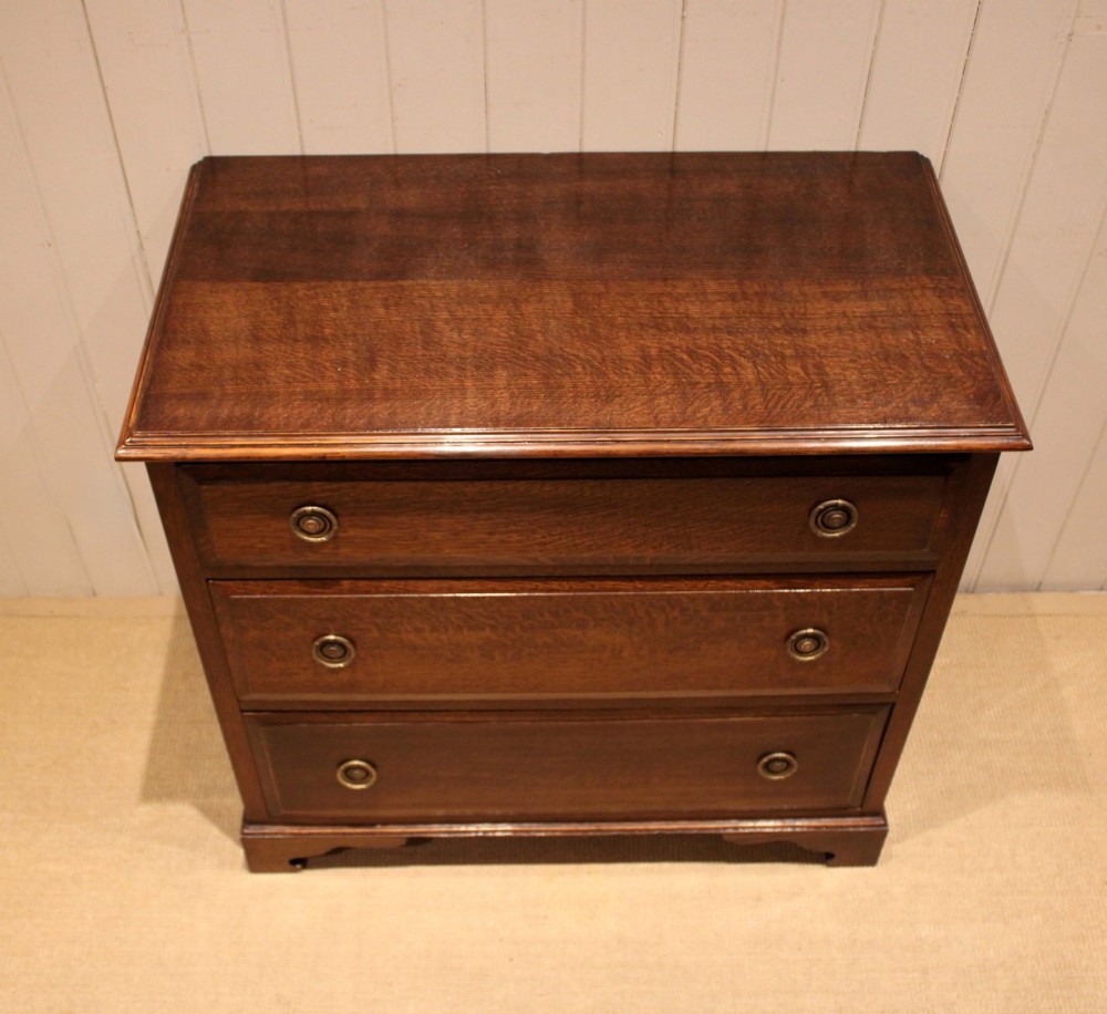 A solid oak chest of drawers featuring three full-width drawers with circular brass drop ring handles and bracket feet. View IX
