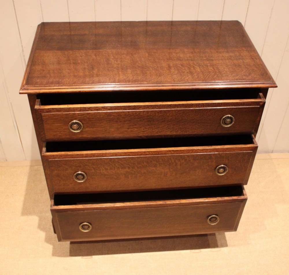 A solid oak chest of drawers featuring three full-width drawers with circular brass drop ring handles and bracket feet. View XII