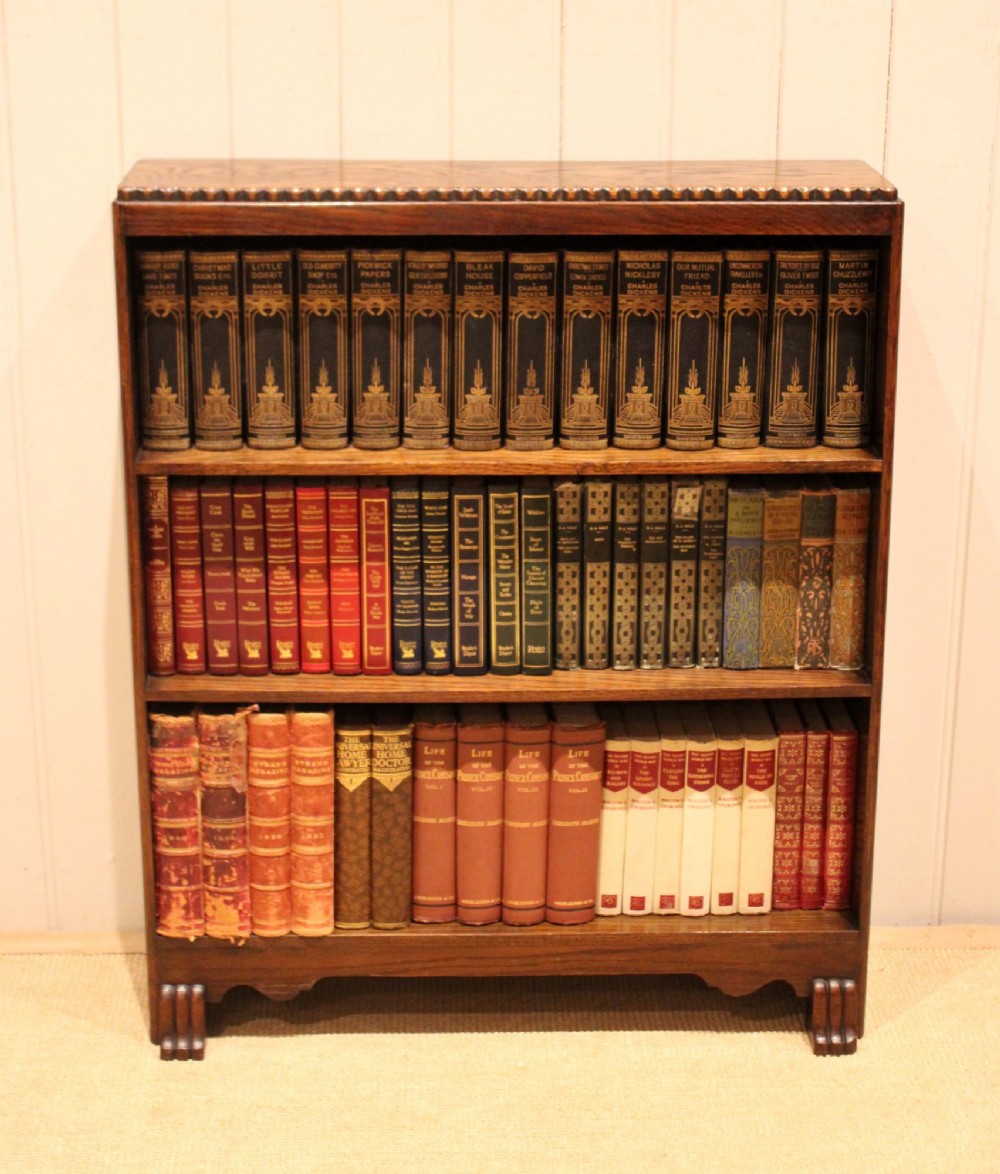 A low dark oak open bookcase with three shelving tiers, a beaded top edge, and fluted bracket feet. View III
