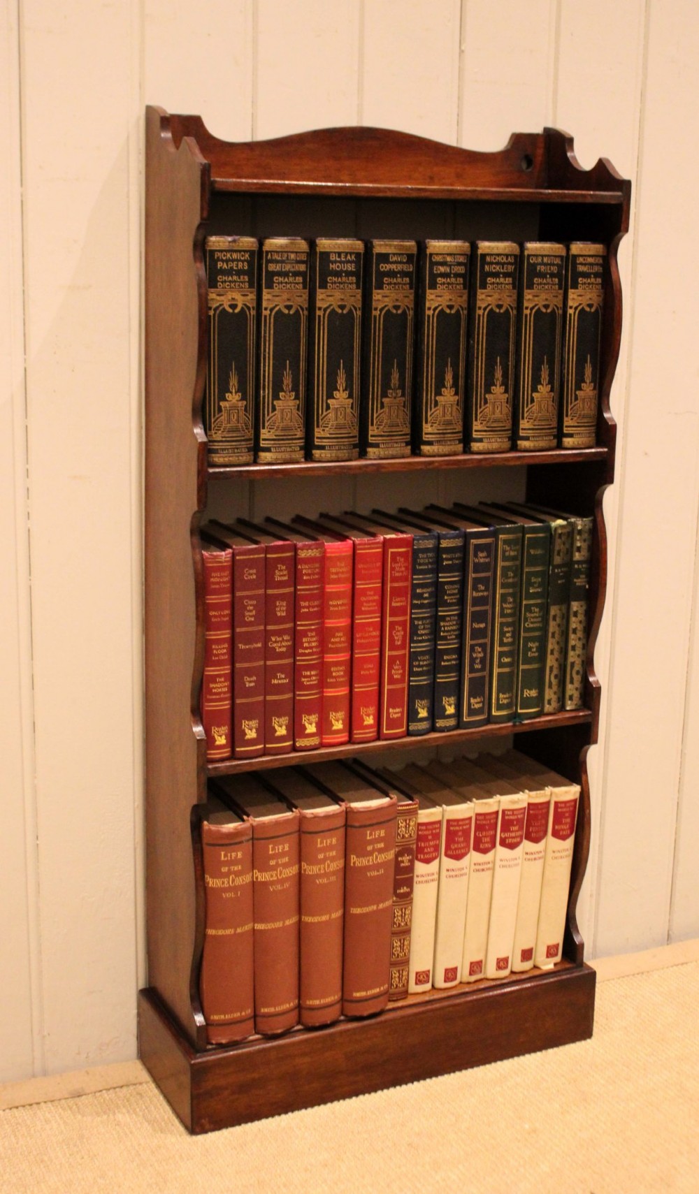A small dark oak open bookcase featuring four tier shelves, shaped side panels, and a scrolled top gallery. View III