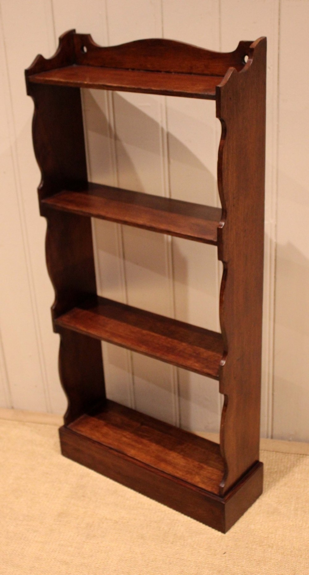 A small dark oak open bookcase featuring four tier shelves, shaped side panels, and a scrolled top gallery. View VIII