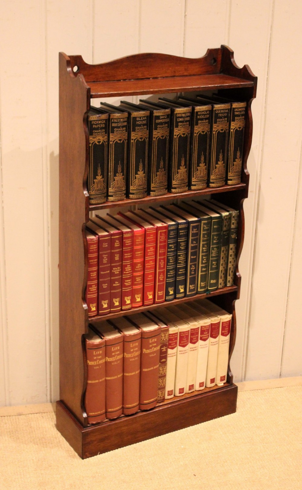 A small dark oak open bookcase featuring four tier shelves, shaped side panels, and a scrolled top gallery. View IX