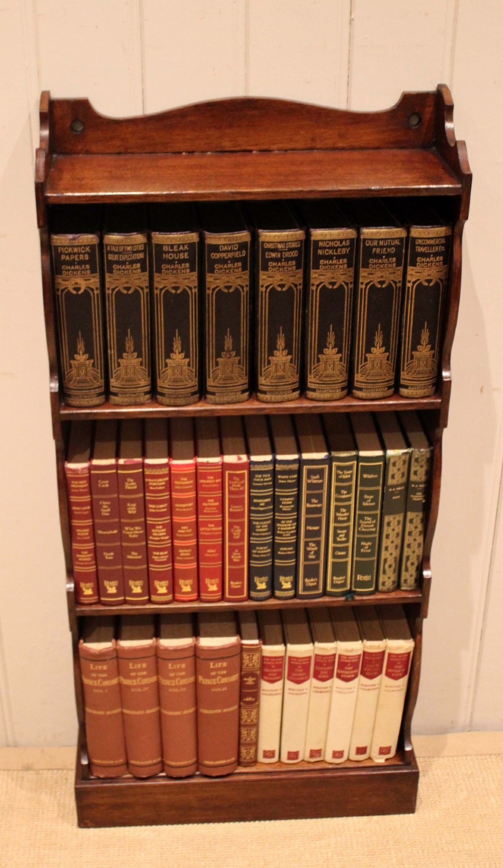 A small dark oak open bookcase featuring four tier shelves, shaped side panels, and a scrolled top gallery. View XII