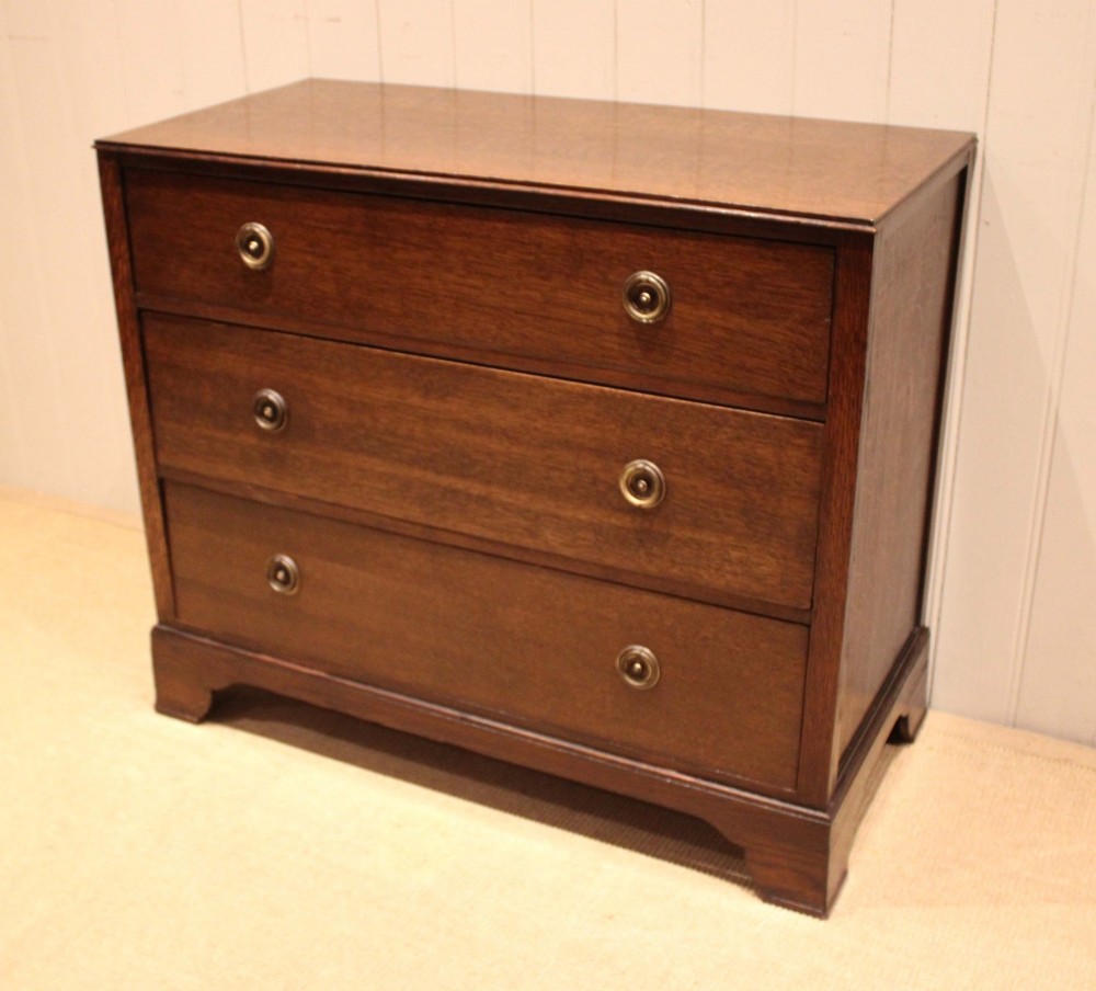 An early 20th-century medium brown oak chest of drawers with three drawers, circular brass ring handles, and bracket feet. View XI