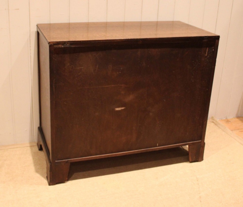 An early 20th-century medium brown oak chest of drawers with three drawers, circular brass ring handles, and bracket feet. View XII