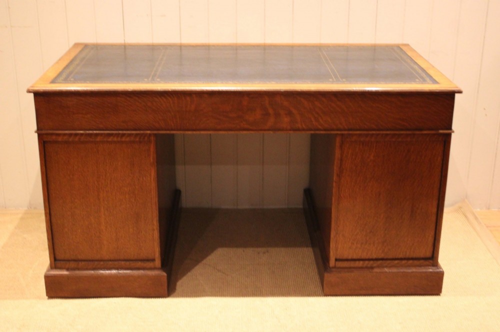 An Edwardian figured oak pedestal desk featuring a dark green leather writing surface and nine drawers with brass handles. View XII