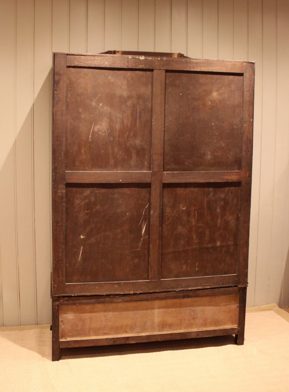 An early twentieth-century warm brown oak wardrobe with a central arched mirror door, carved foliate border mouldings, and a single lower drawer. View XIII